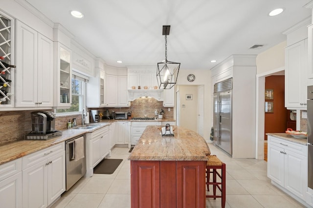 kitchen with light tile patterned floors, stainless steel appliances, a kitchen island, a sink, and visible vents