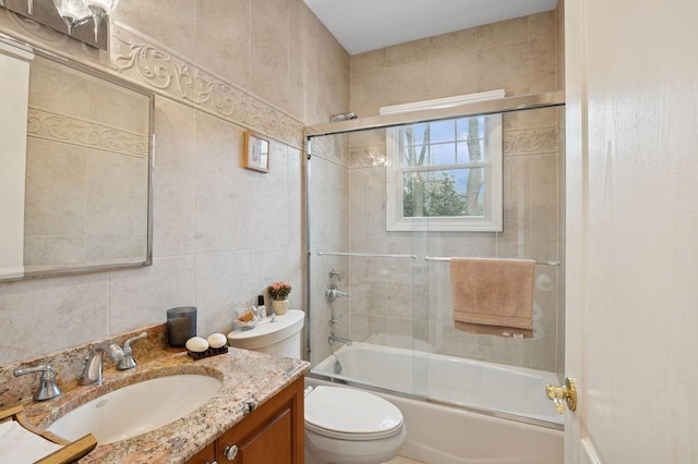 full bathroom with combined bath / shower with glass door, tile walls, toilet, and vanity