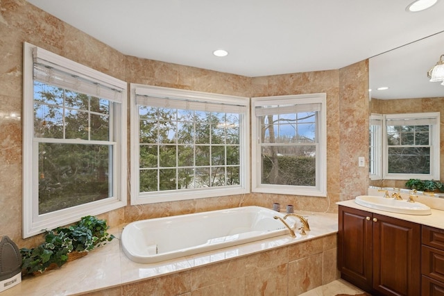 bathroom with a bath, vanity, a wealth of natural light, and tile walls