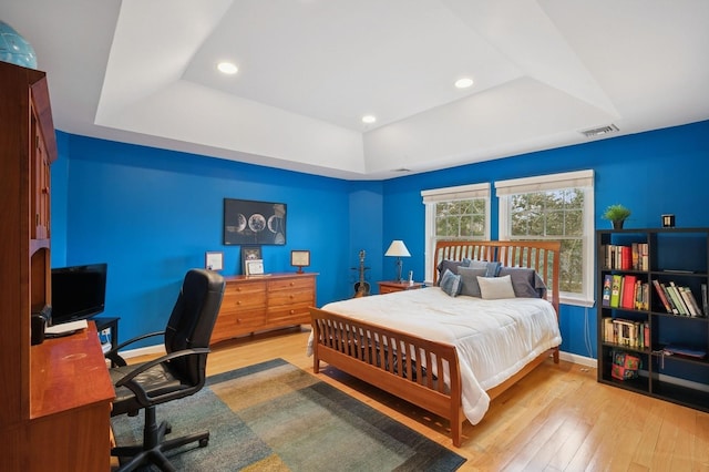 bedroom featuring wood-type flooring, a raised ceiling, visible vents, and recessed lighting