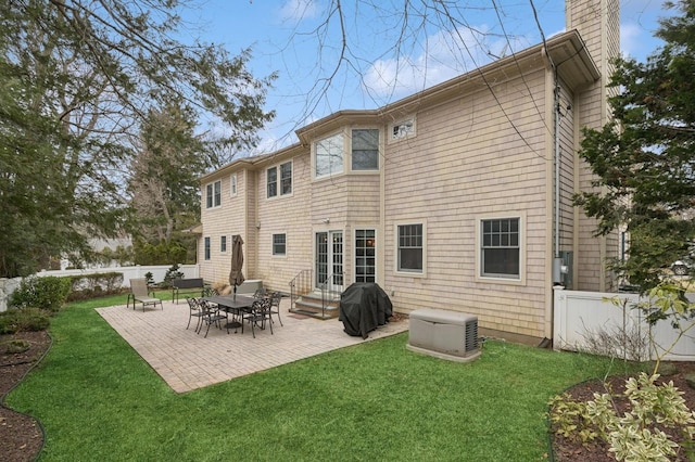 rear view of property with entry steps, a lawn, a chimney, and fence