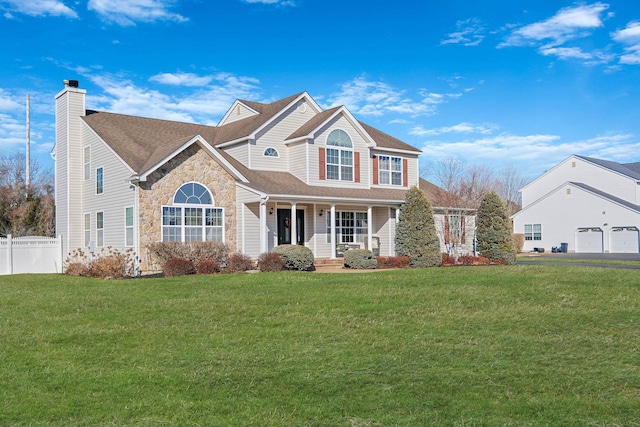 view of front of house with stone siding, a front lawn, a chimney, and fence