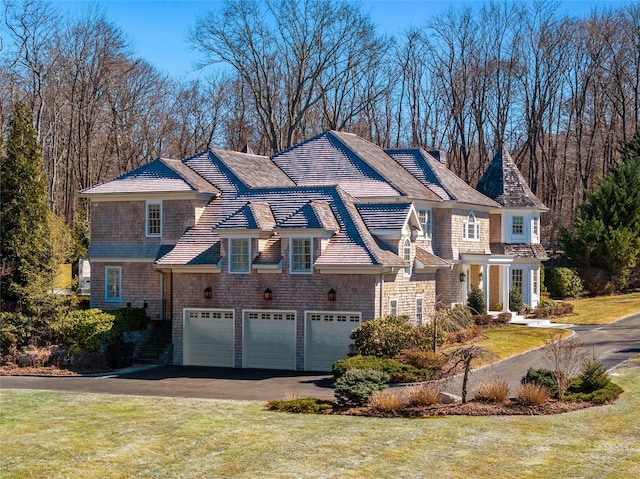 shingle-style home with a garage, driveway, and a front lawn