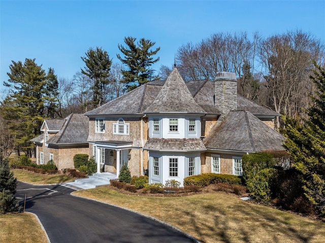 shingle-style home featuring driveway and a front lawn