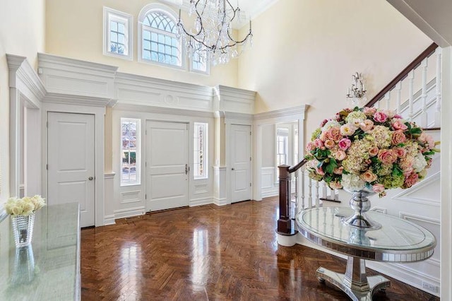 entryway featuring a towering ceiling, plenty of natural light, stairway, and a decorative wall