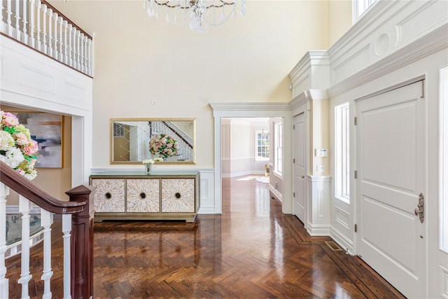 foyer featuring stairs, a high ceiling, a wainscoted wall, and a decorative wall