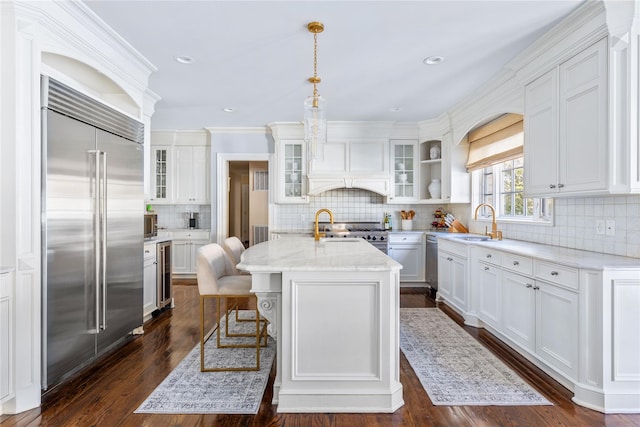 kitchen with beverage cooler, high quality appliances, a kitchen island with sink, premium range hood, and a sink