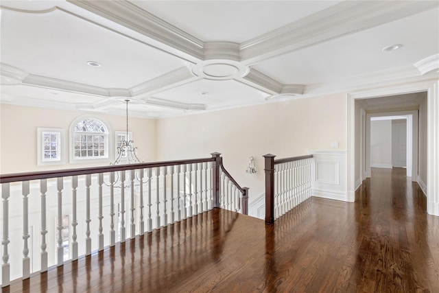 corridor featuring coffered ceiling, ornamental molding, wood finished floors, an inviting chandelier, and an upstairs landing