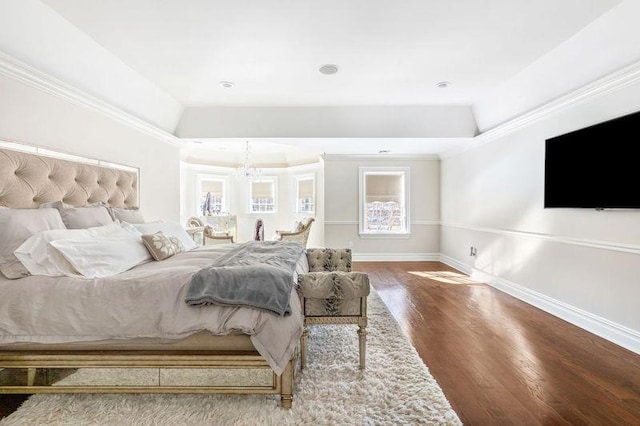 bedroom with baseboards, multiple windows, a tray ceiling, and wood finished floors