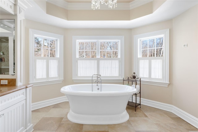 full bathroom featuring tile patterned flooring, a freestanding tub, crown molding, and baseboards