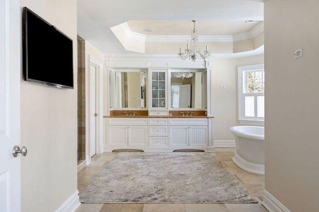 bathroom featuring a raised ceiling, a freestanding tub, a sink, and double vanity