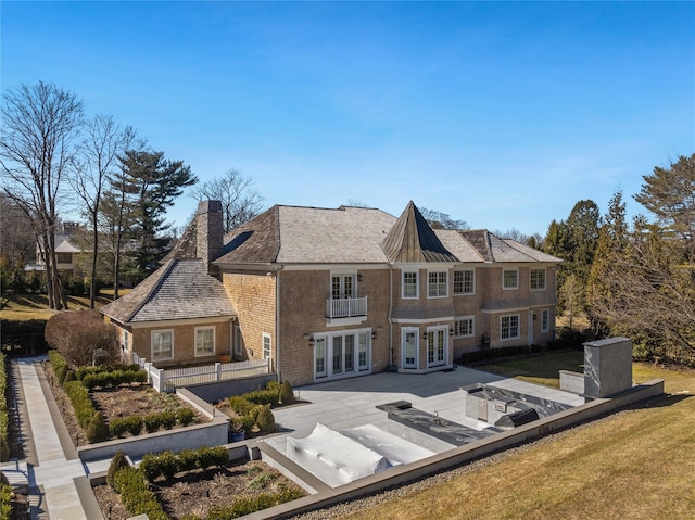 rear view of property featuring a yard, a chimney, and french doors