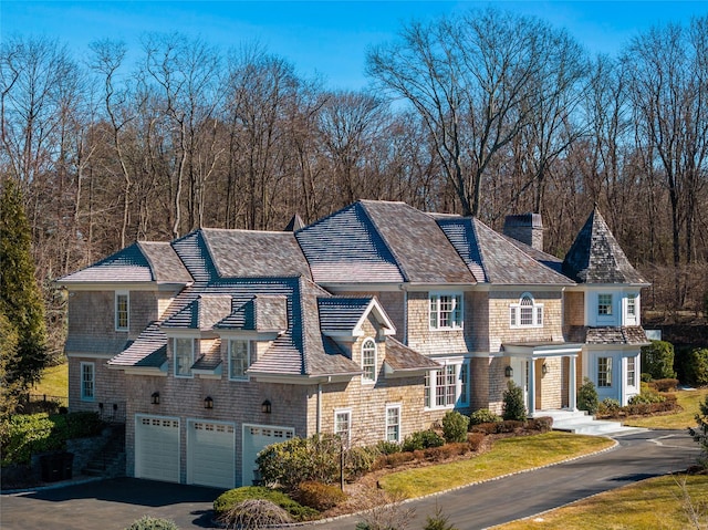 shingle-style home featuring a garage, aphalt driveway, and a chimney