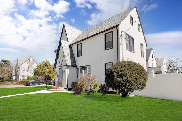 exterior space featuring a high end roof, a lawn, stucco siding, and fence