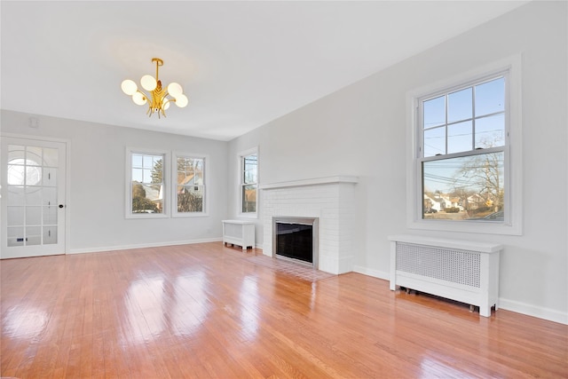 unfurnished living room featuring radiator, baseboards, a chandelier, and wood finished floors