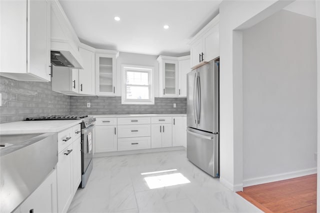 kitchen with white cabinetry, stainless steel appliances, decorative backsplash, and light countertops