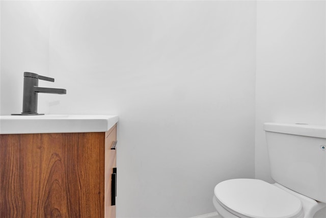 half bathroom with toilet, baseboards, and vanity