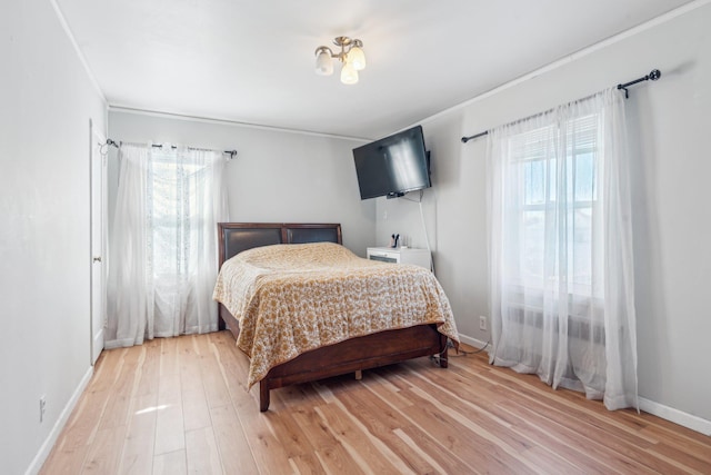 bedroom with crown molding, multiple windows, baseboards, and light wood-type flooring