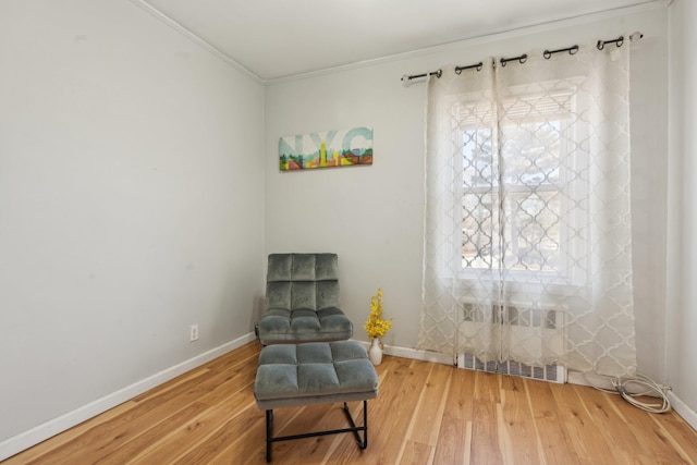 sitting room with baseboards, light wood finished floors, and ornamental molding