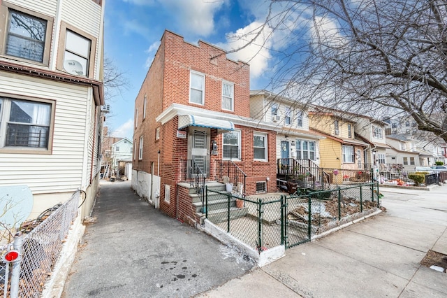 view of front of house featuring entry steps, brick siding, a fenced front yard, and a residential view