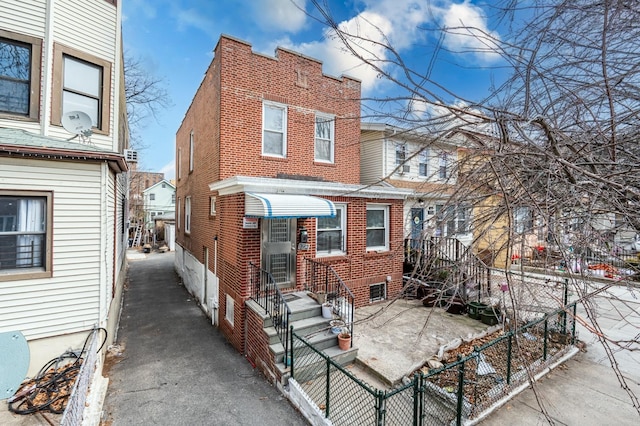 exterior space featuring entry steps, brick siding, and fence