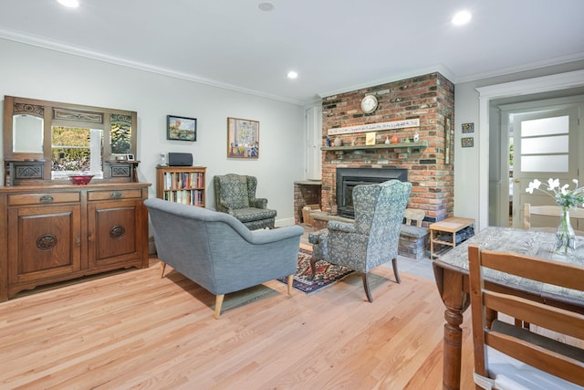 living area with light wood finished floors, recessed lighting, a brick fireplace, and crown molding