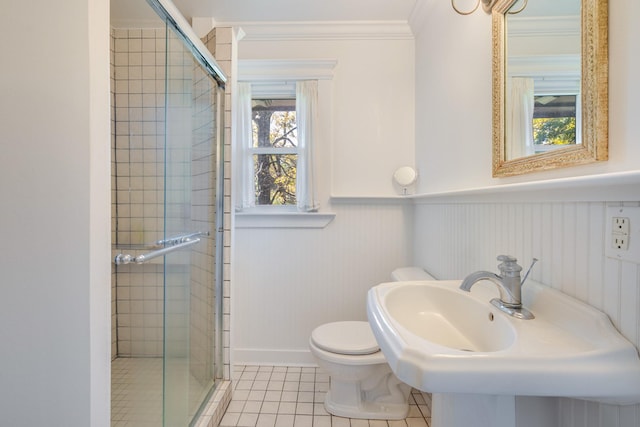 full bath with tile patterned flooring, crown molding, a stall shower, and wainscoting