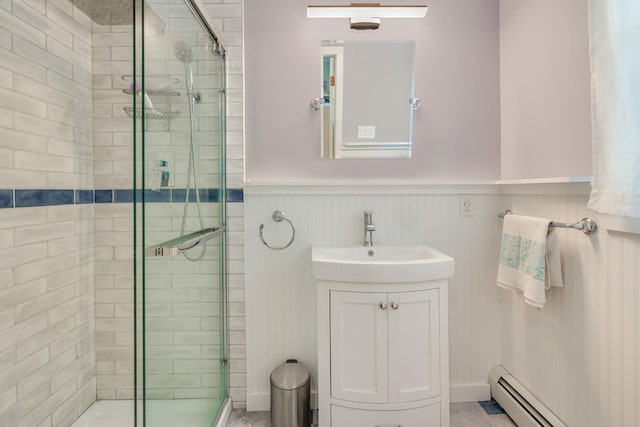 bathroom with a wainscoted wall, vanity, baseboard heating, and a shower stall