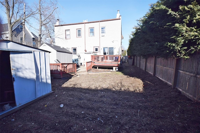 back of house with a deck, a shed, an outdoor structure, and fence