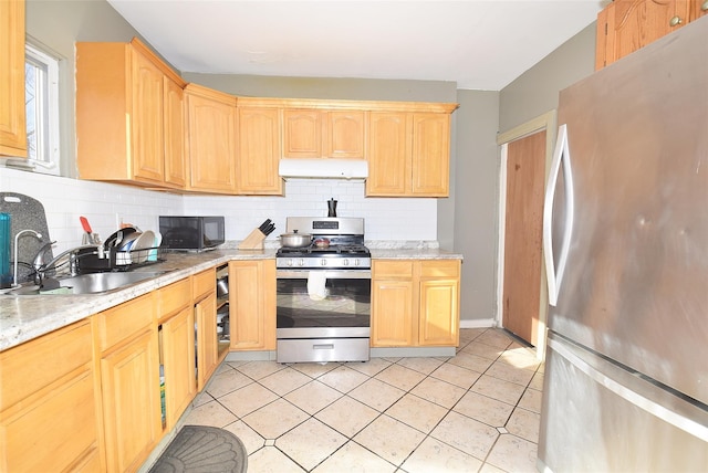 kitchen with light tile patterned flooring, under cabinet range hood, stainless steel appliances, a sink, and backsplash