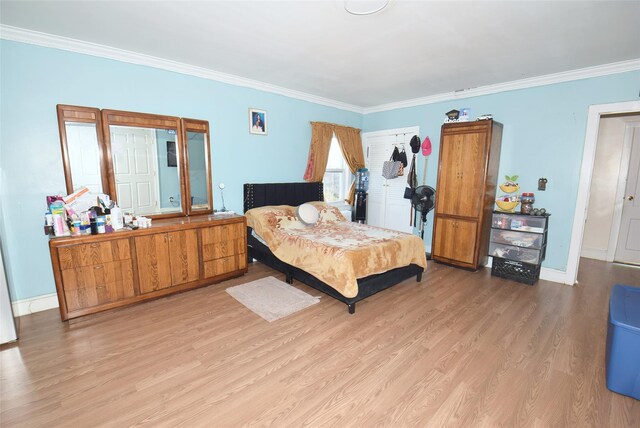 bedroom with ornamental molding, light wood-style flooring, and baseboards