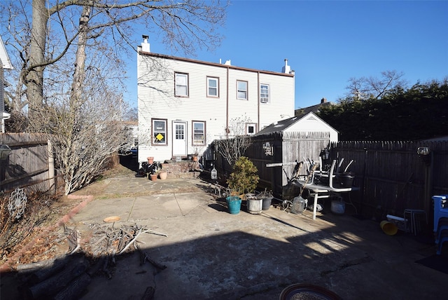 back of property featuring entry steps, a patio area, a fenced backyard, and a chimney