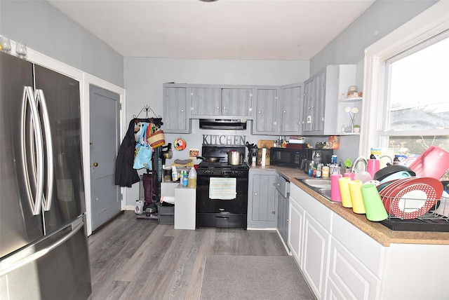 kitchen featuring extractor fan, gray cabinetry, wood finished floors, a sink, and black appliances