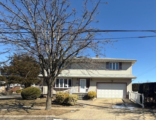 traditional-style house featuring concrete driveway, fence, and an attached garage