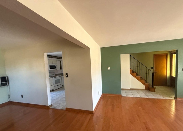 unfurnished room featuring stairs, baseboards, and wood finished floors