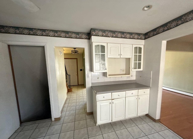 kitchen featuring light tile patterned floors, baseboard heating, glass insert cabinets, and white cabinetry