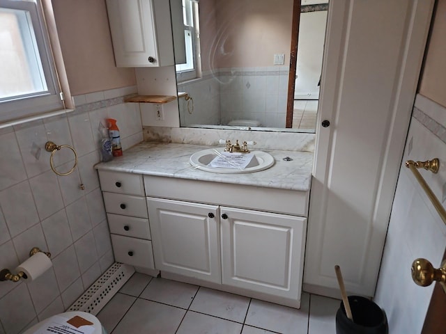 bathroom featuring toilet, a wealth of natural light, tile patterned flooring, and tile walls