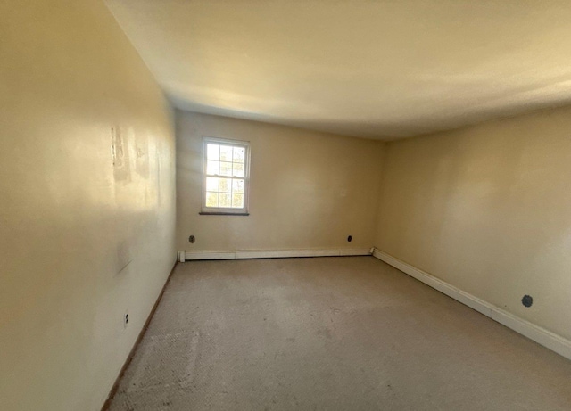 empty room with carpet floors, a baseboard radiator, and baseboards