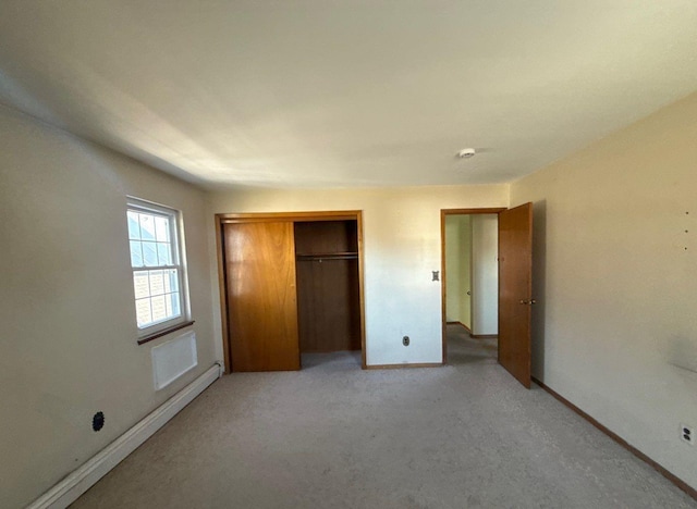 unfurnished bedroom with baseboards, a closet, and light colored carpet