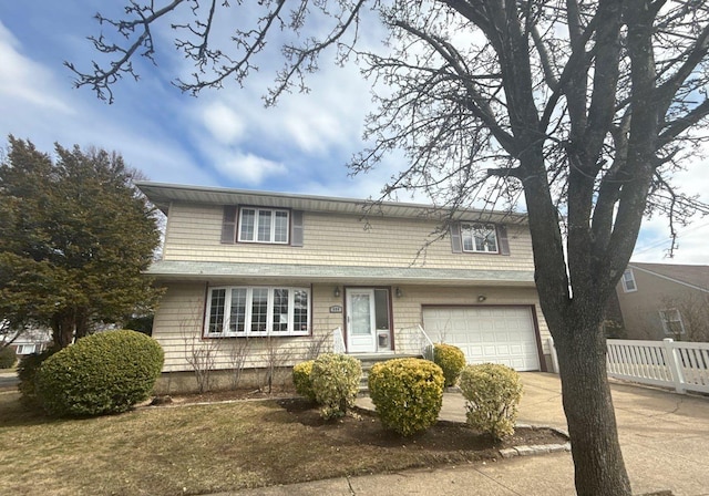 traditional home with an attached garage, concrete driveway, and fence