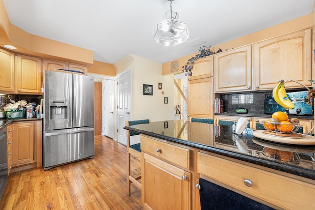 kitchen with light wood-style flooring, decorative backsplash, light brown cabinets, dark stone countertops, and stainless steel fridge with ice dispenser