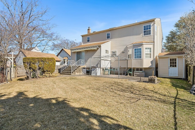 rear view of house with a yard, a chimney, a storage unit, fence, and an outdoor structure