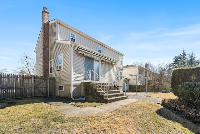 rear view of house with cooling unit, fence, a chimney, and a lawn