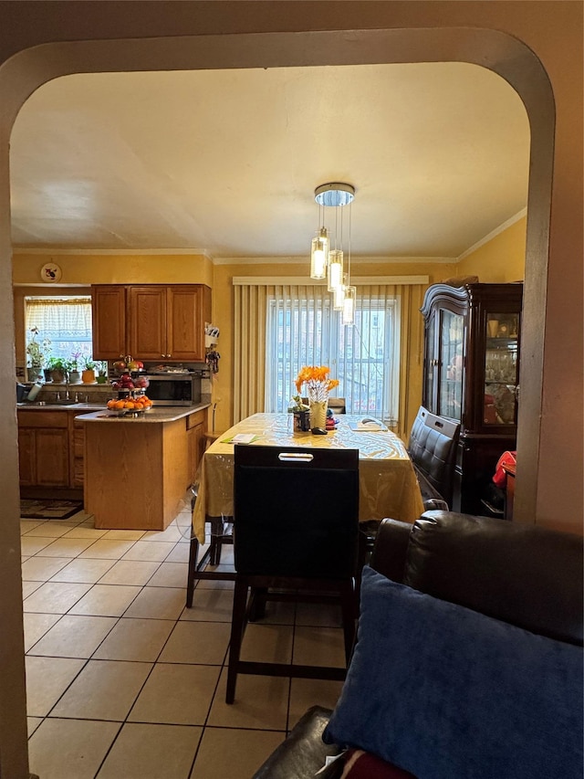 dining area with light tile patterned floors, arched walkways, and crown molding