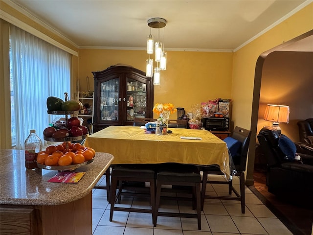 dining space with arched walkways, light tile patterned flooring, and crown molding