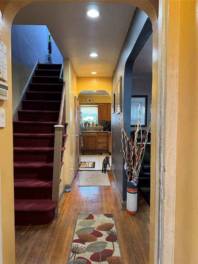 hall with stairway, recessed lighting, light wood-style floors, and arched walkways