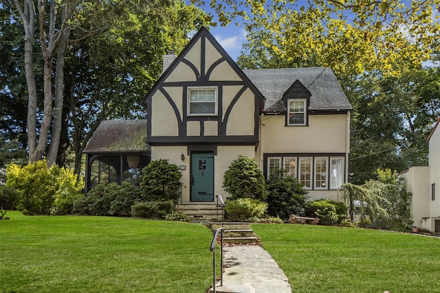 tudor house featuring brick siding, stucco siding, a front lawn, and a chimney