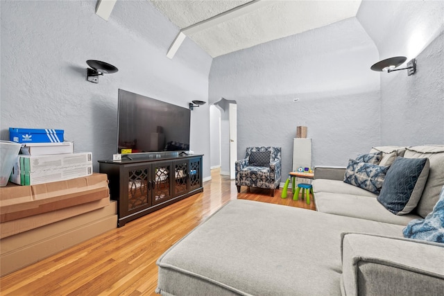 living area with lofted ceiling, a textured ceiling, wood finished floors, and a textured wall