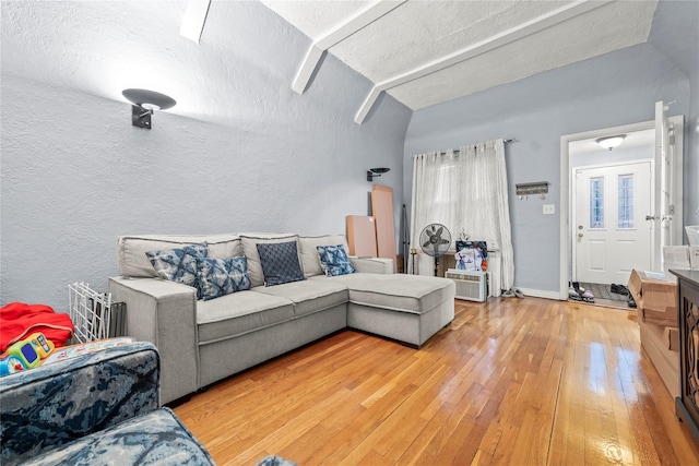 living area with lofted ceiling, a textured wall, a textured ceiling, baseboards, and light wood finished floors