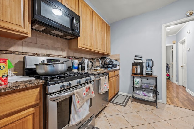 kitchen featuring baseboards, stainless steel appliances, decorative backsplash, and light tile patterned flooring